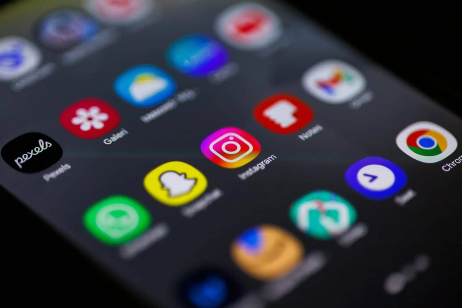 Close-up view of smartphone home screen featuring popular apps like Instagram, Snapchat, and Chrome.